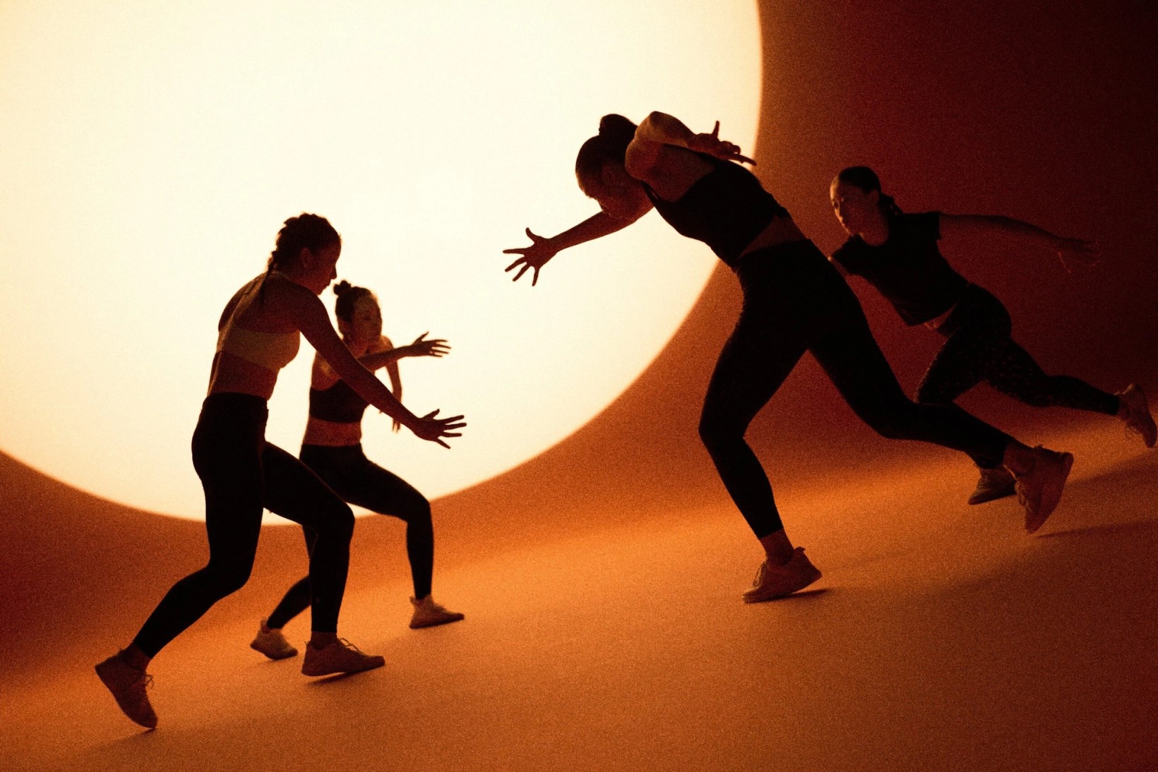 Silhouetted women sparring in front of a large glowing circle