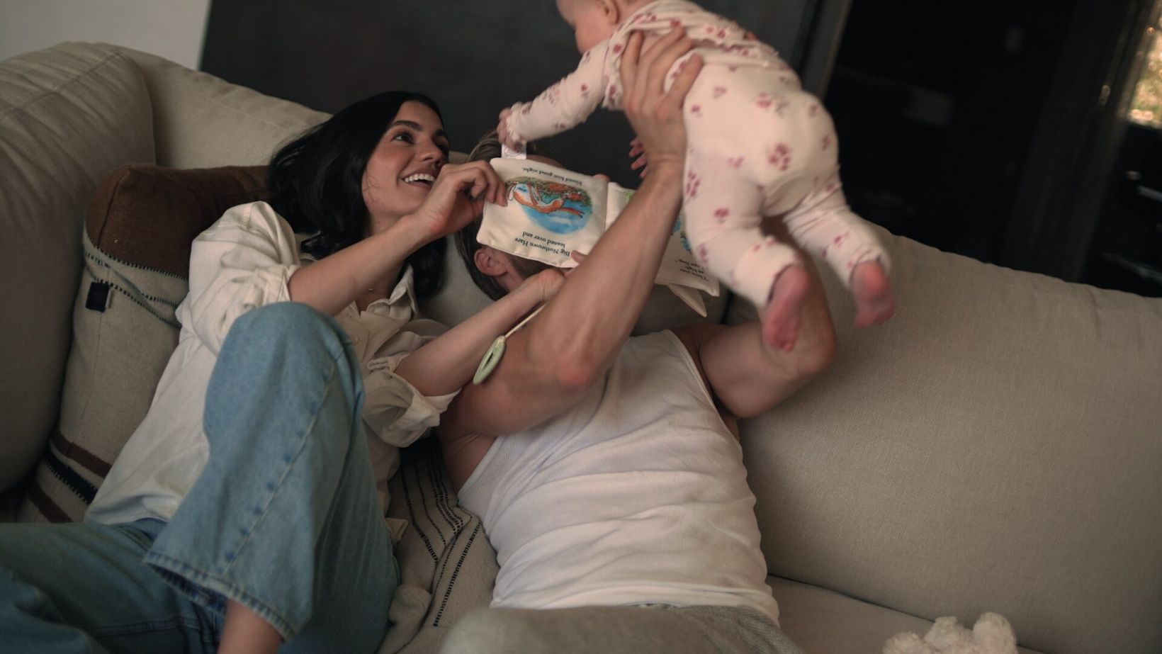 Hayley Erbert on the sofa lifting the baby overhead