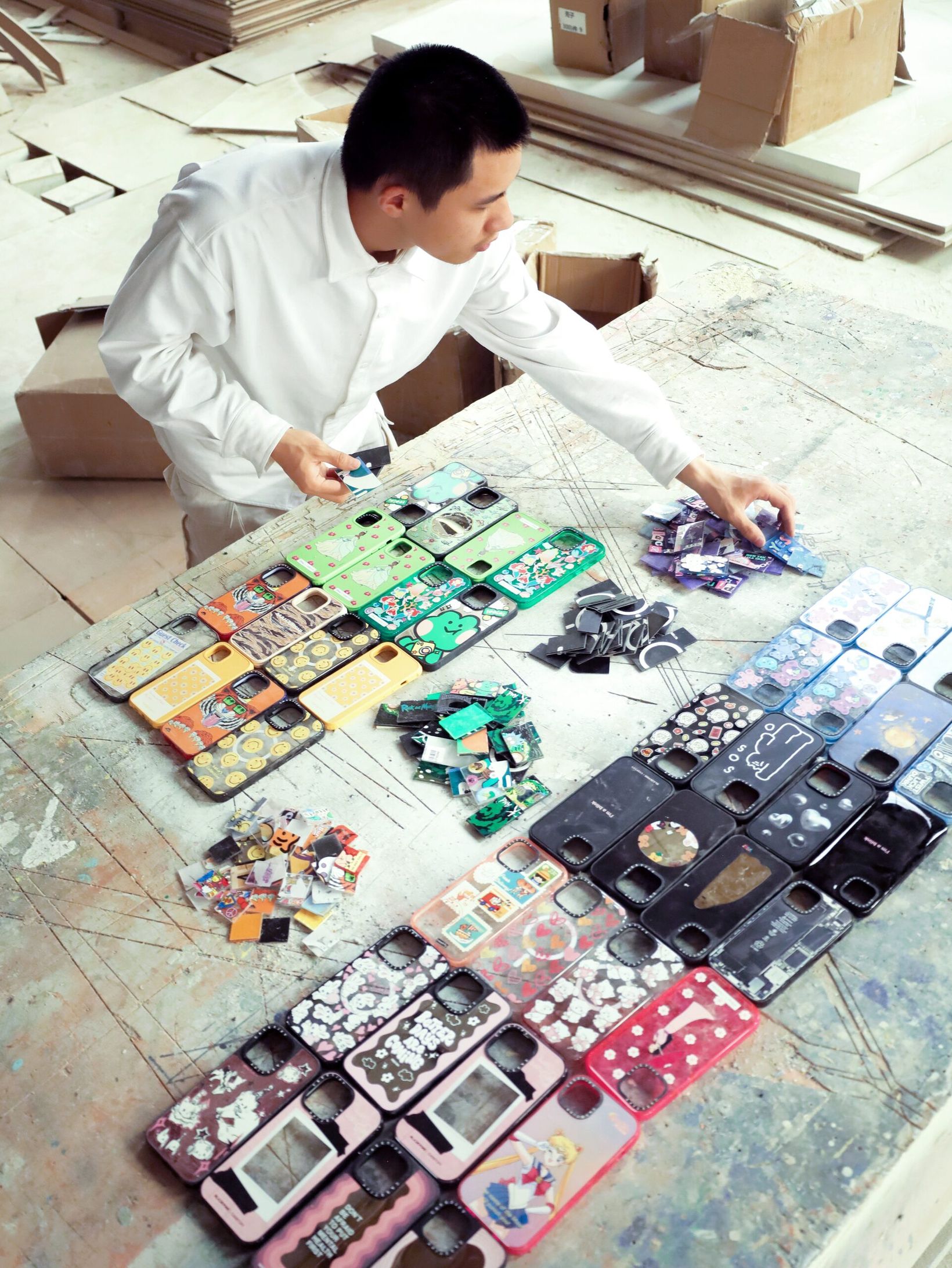Artist sorting old phone cases by colour on a workshop table