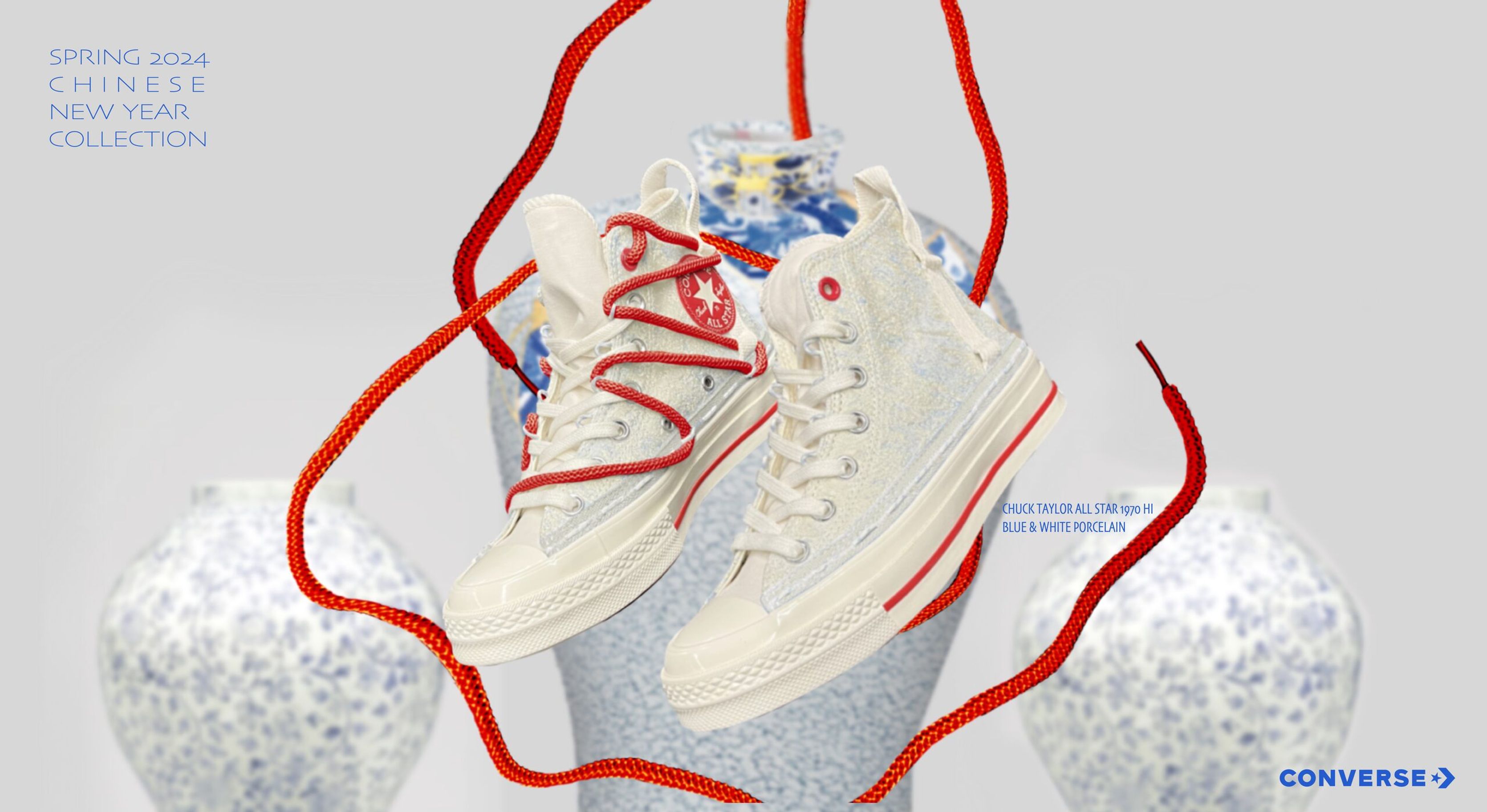 Cream Converse high-tops with blue dragon details wrapped in red laces on a porcelain vase