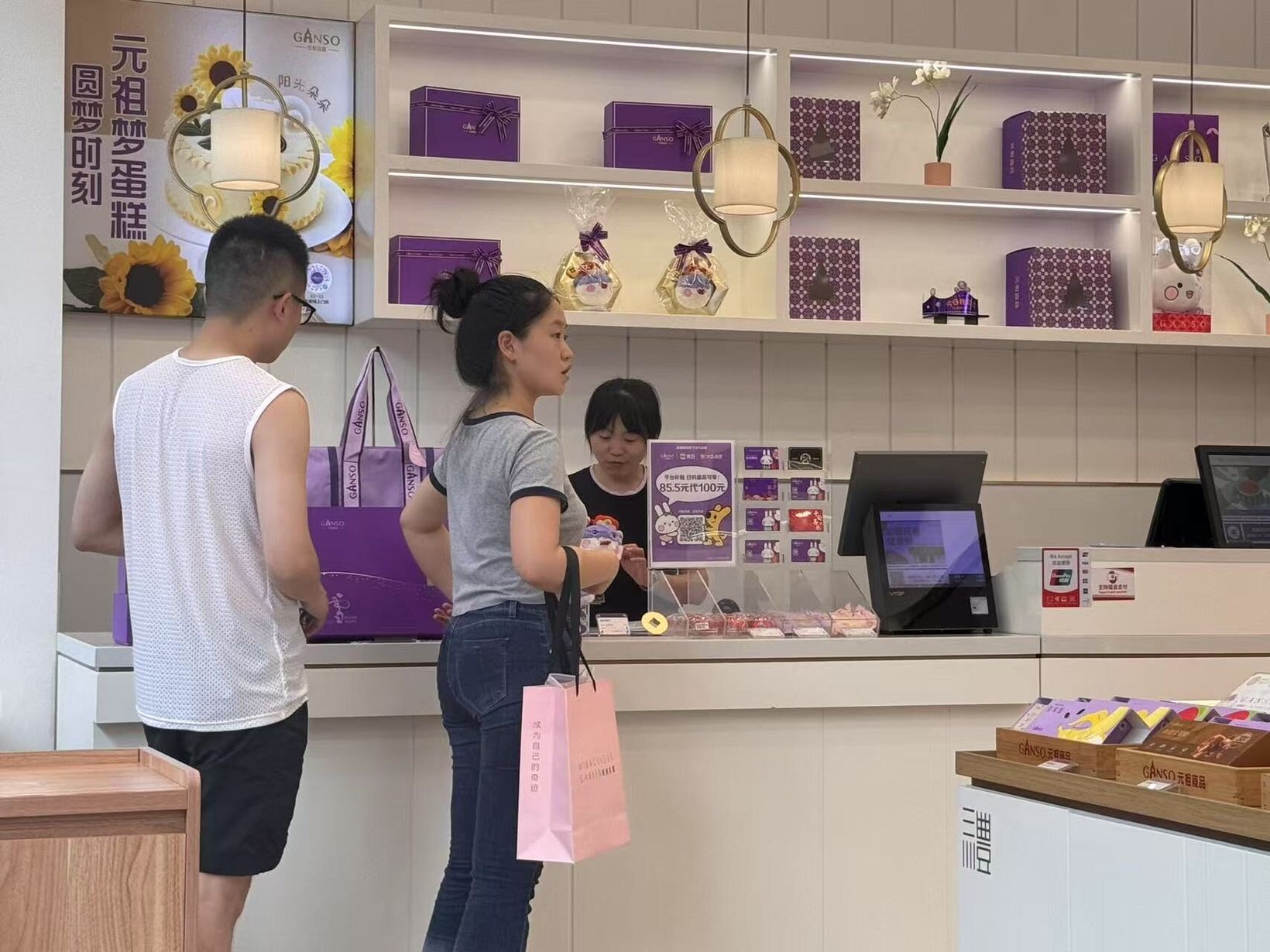 Customers at the counter of a GANSO store with purple gift boxes