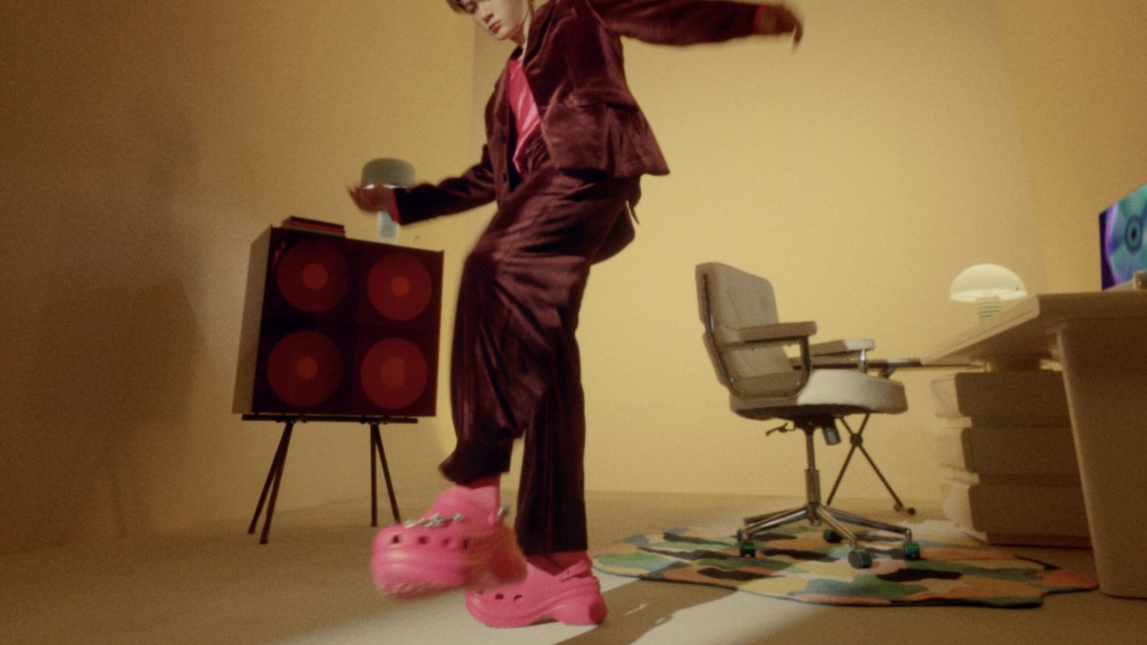 Film still of Tan Jianci dancing beside a speaker in pink Crocs