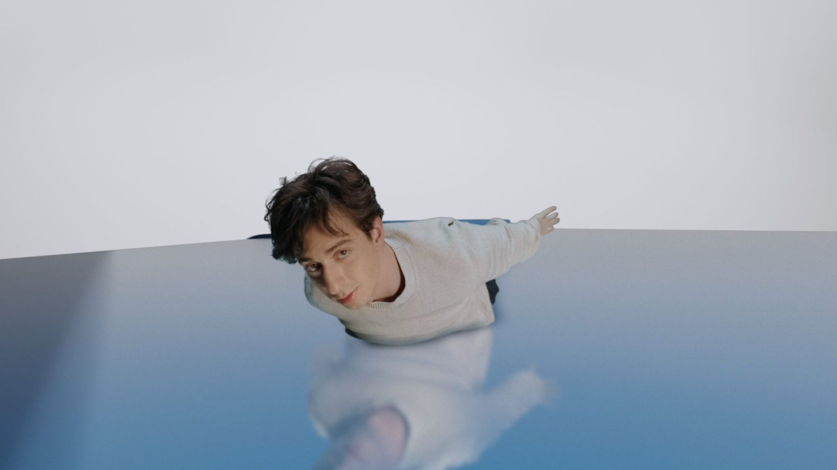 Young man gliding over a reflective blue surface