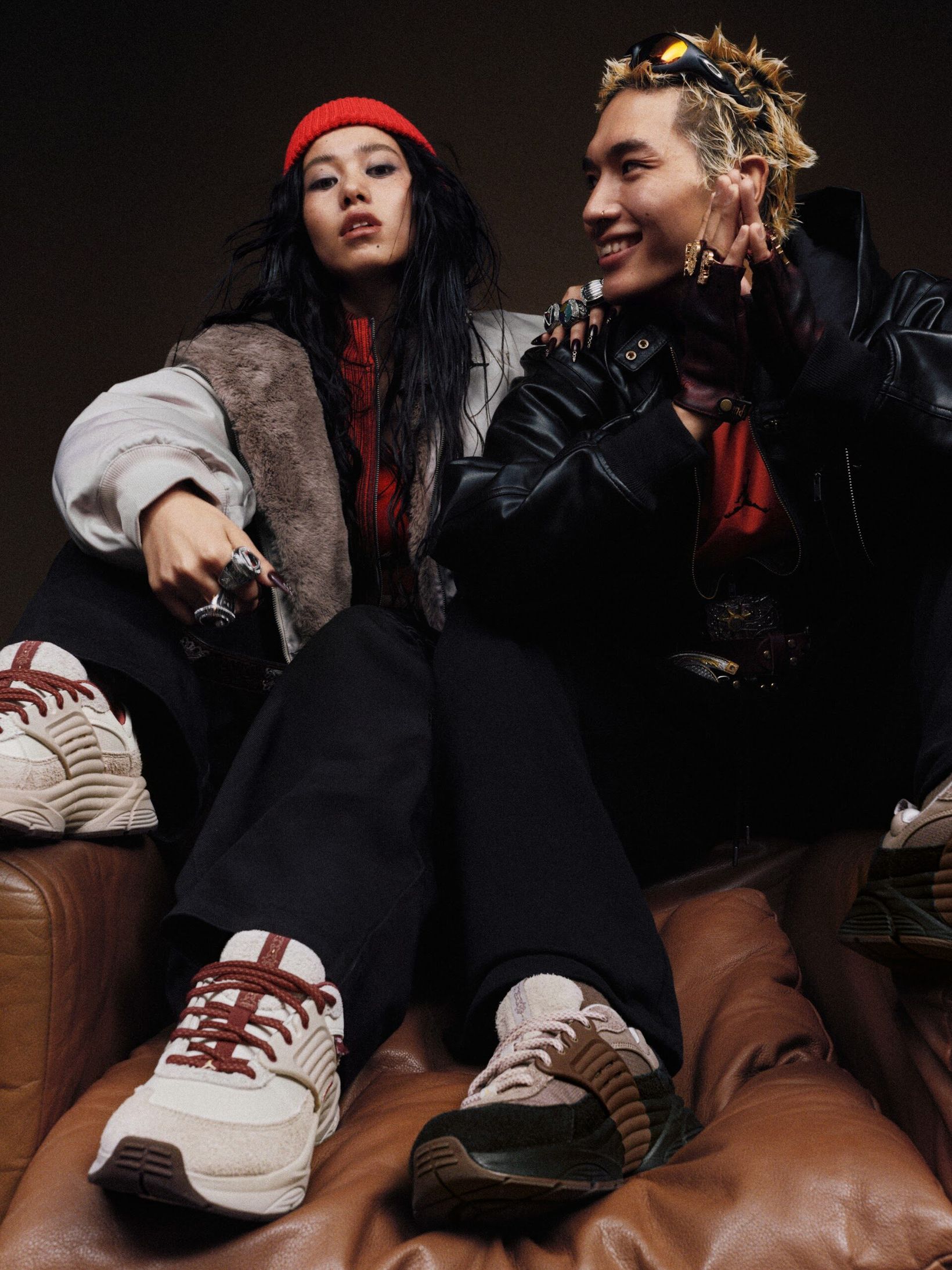 Two models lounging on a leather sofa in Jordan sneakers
