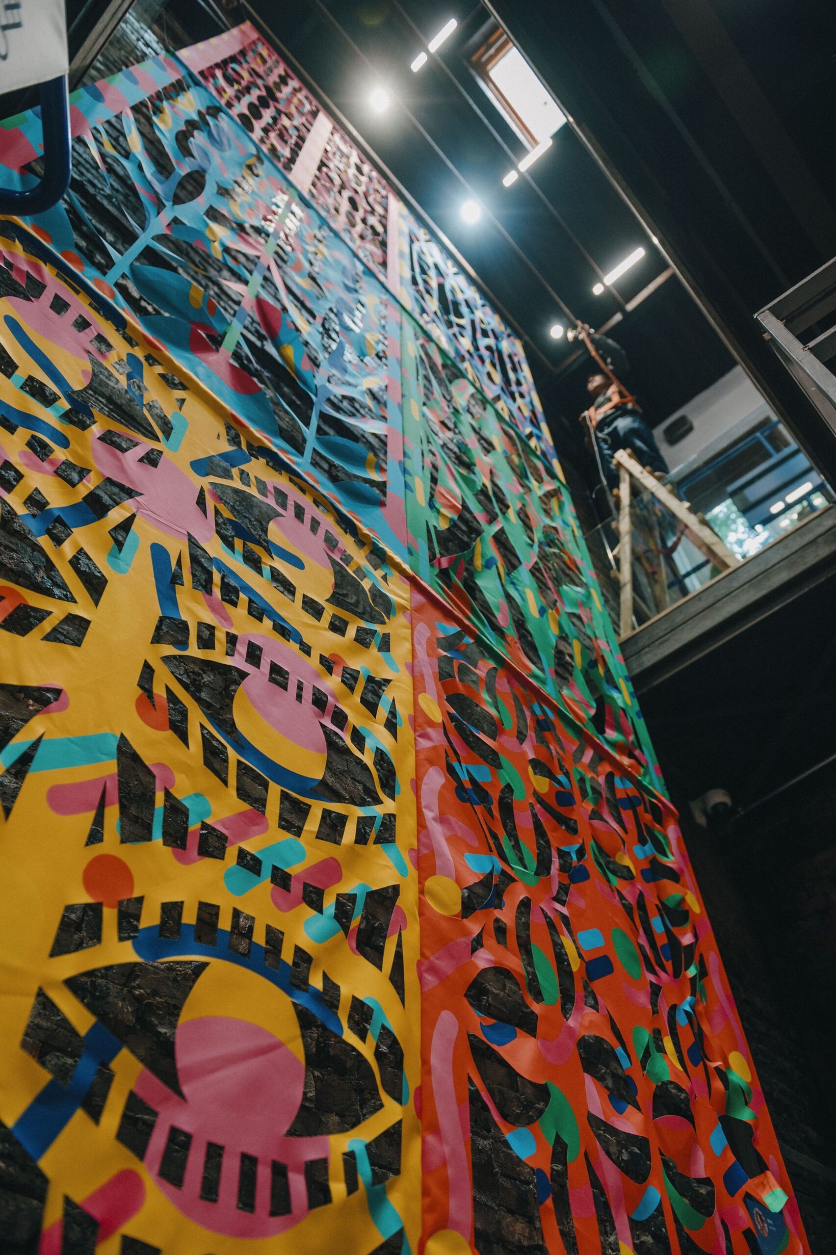 Large patterned mural painted on a tall panel in the exhibition