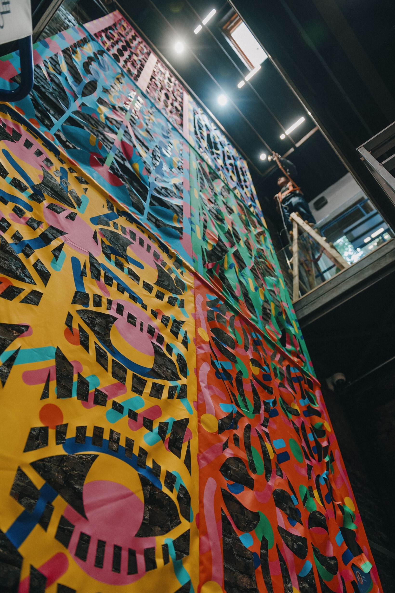 Large patterned mural painted on a tall panel in the exhibition