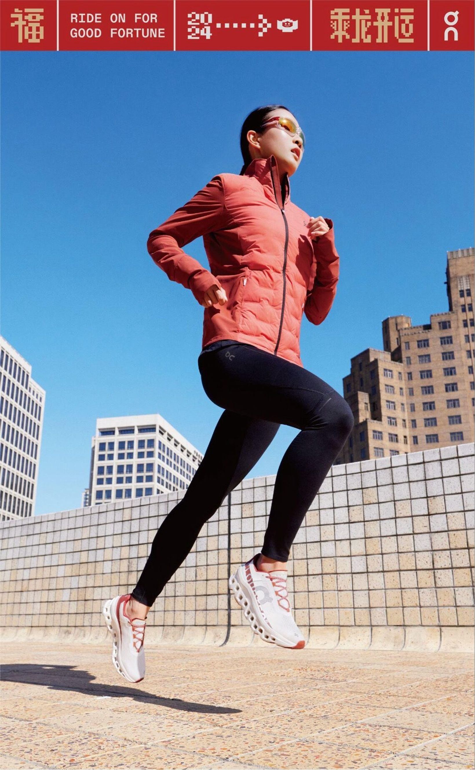 Runner in a red On jacket mid-stride against a blue sky