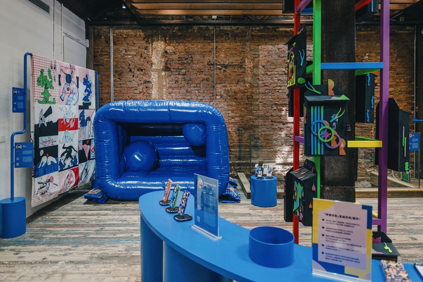 Exhibition hall with a blue inflatable sofa and a painted shelving sculpture