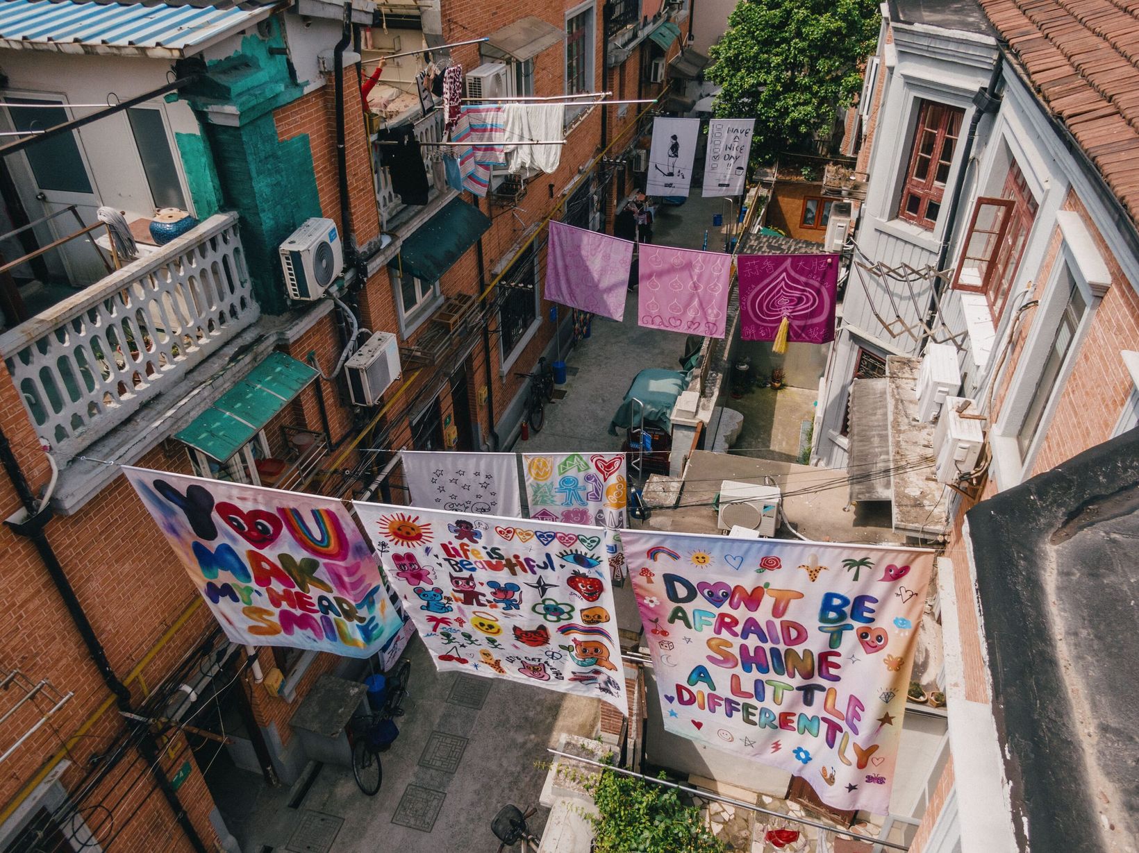 Artist-designed sheets hung across a longtang alley seen from above