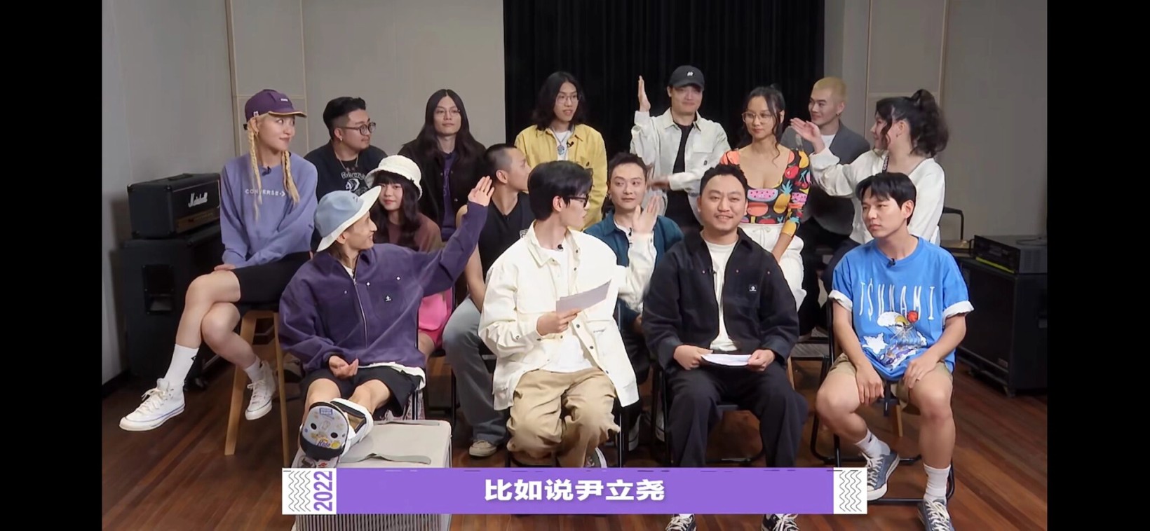 Group of artists seated together in a variety show still