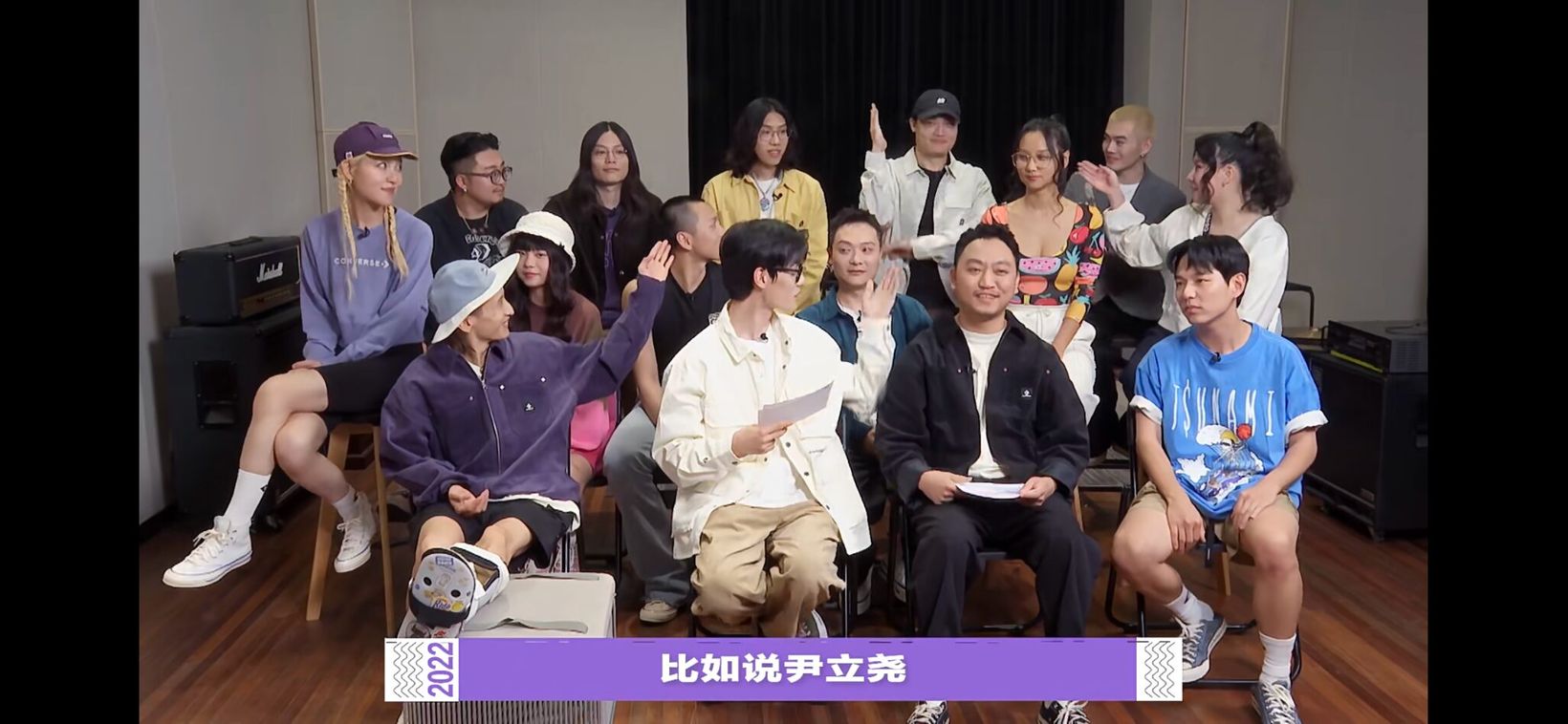 Group of artists seated together in a variety show still