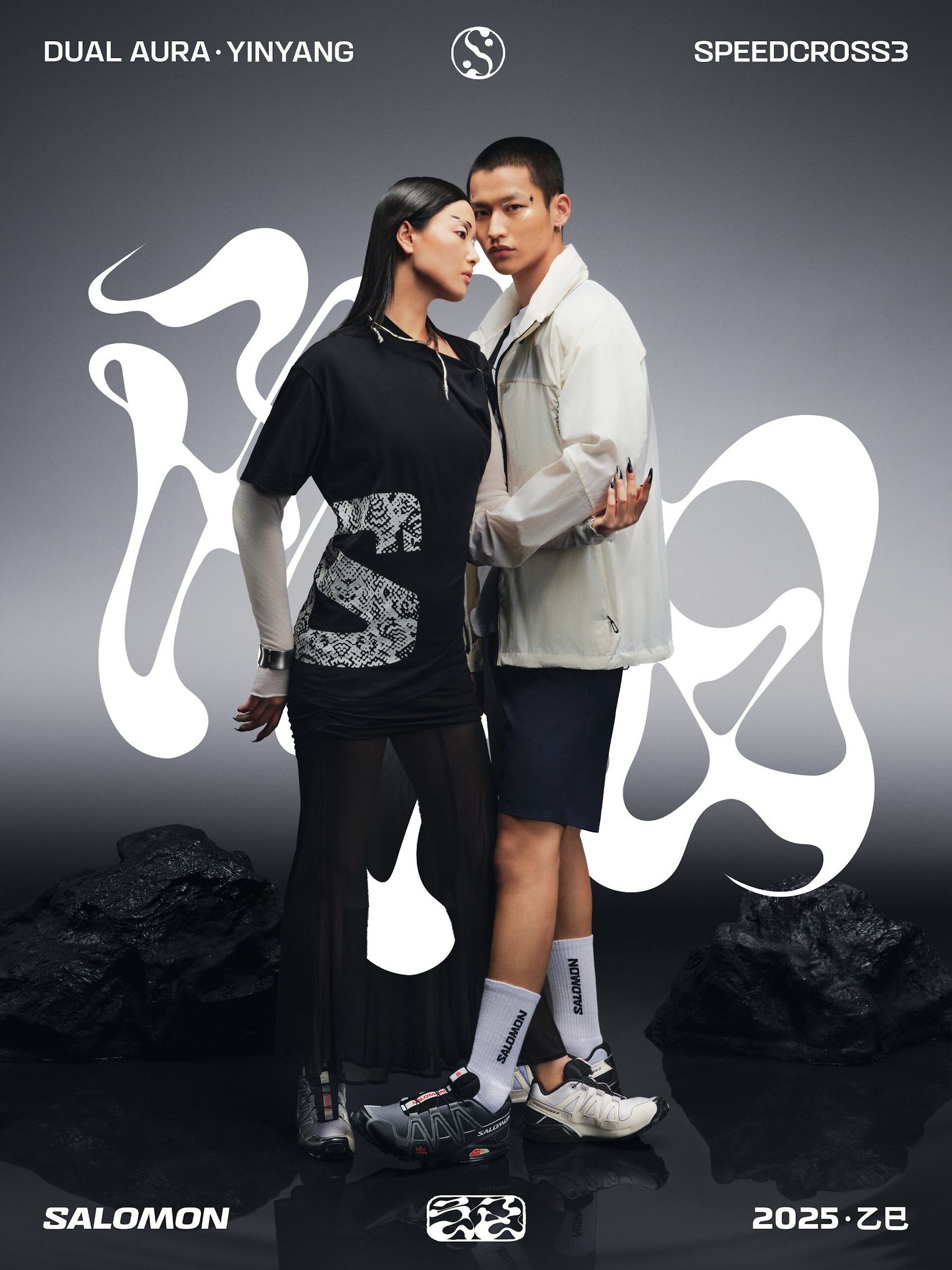 Couple standing among black rocks with white calligraphic forms in the Yin Yang key visual