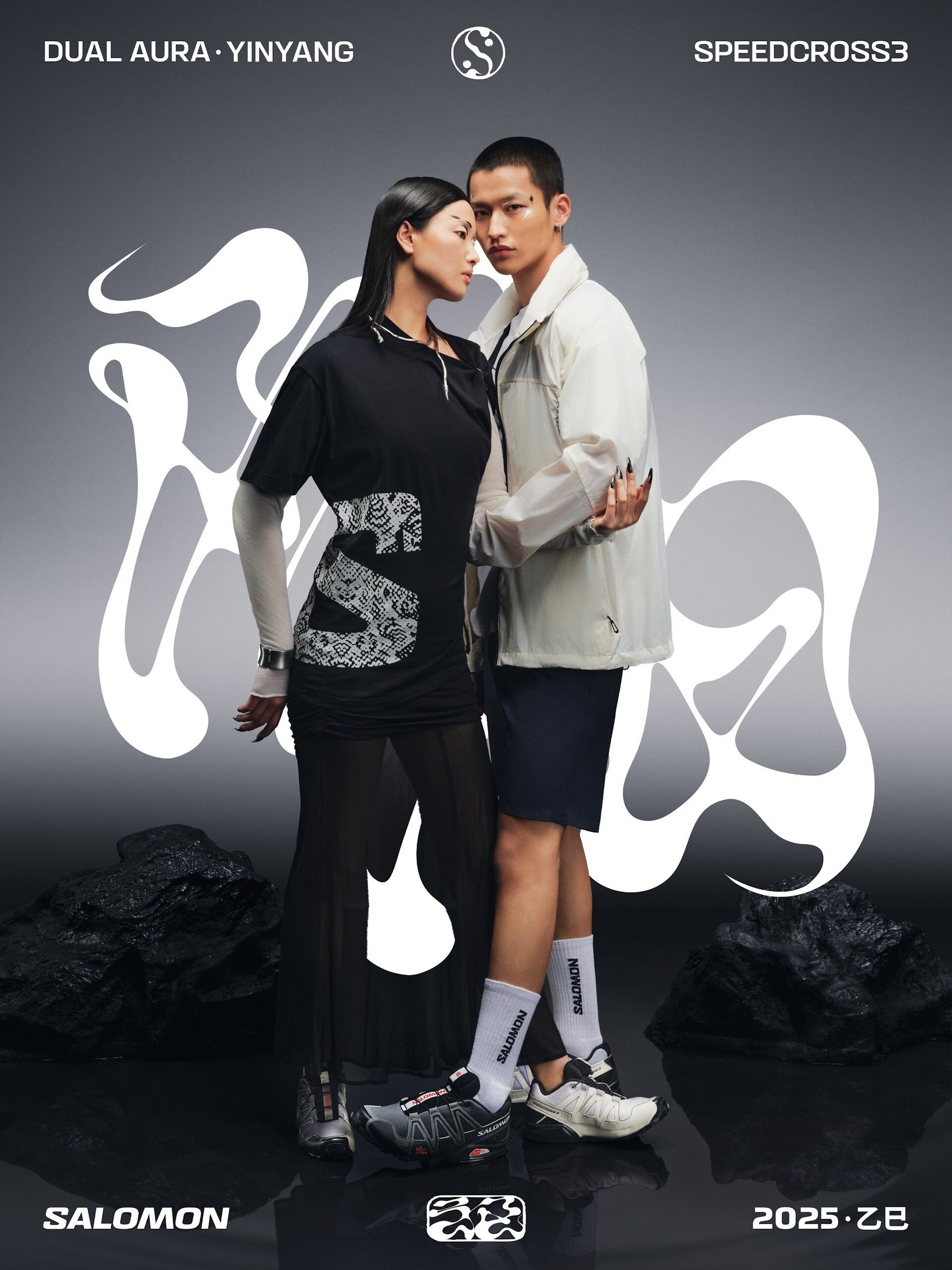 Couple standing among black rocks with white calligraphic forms in the Yin Yang key visual