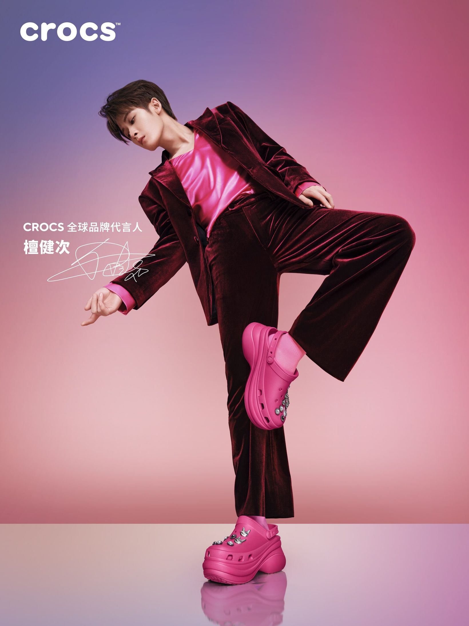 Tan Jianci in a velvet suit posing in pink Crocs Bae clogs