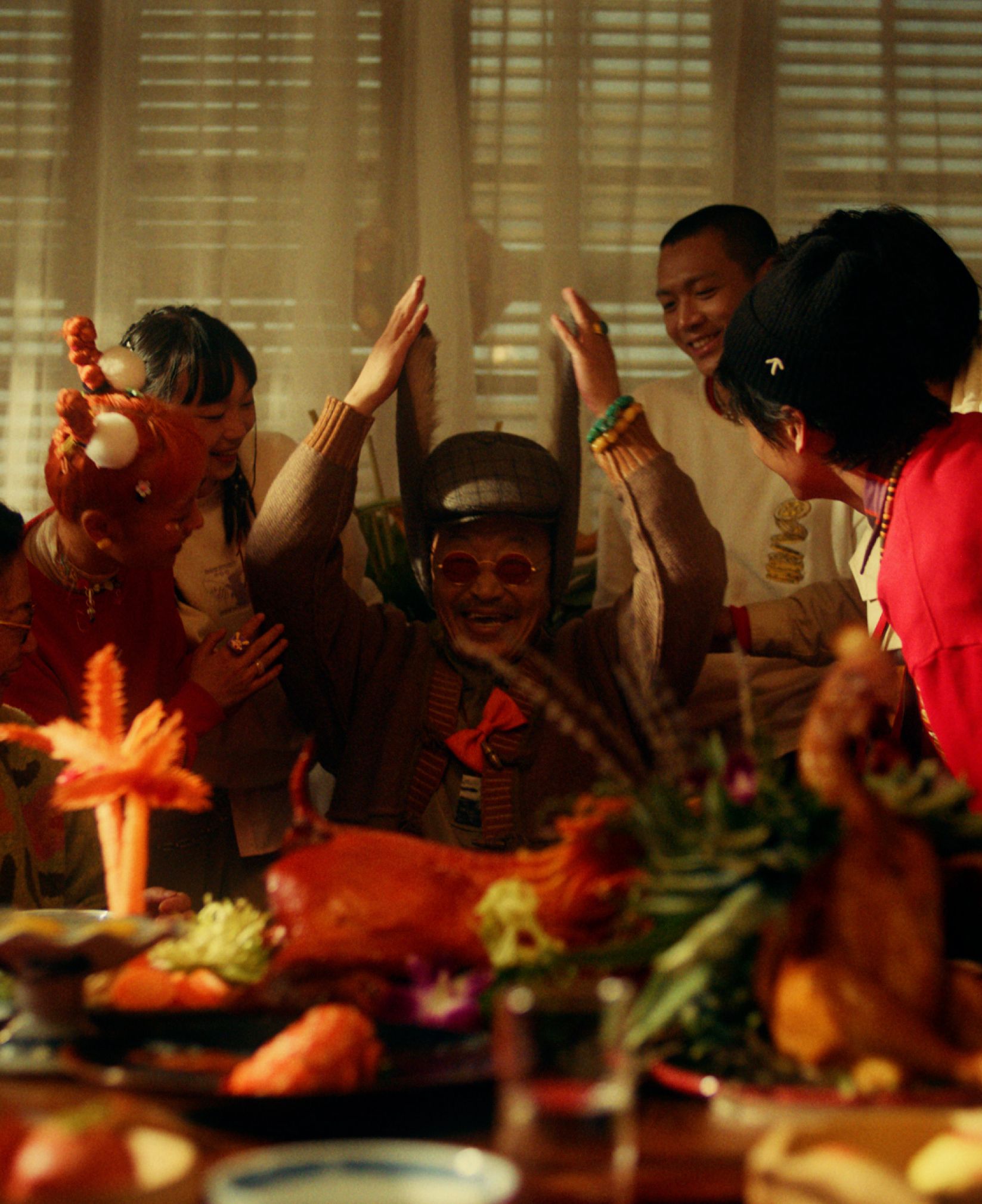 Friends in Converse CNY outfits raising their hands over a New Year banquet table