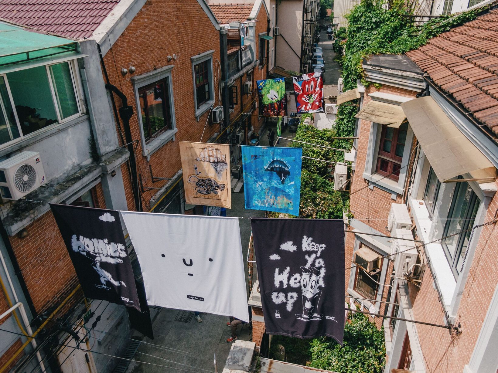 Black and white artwork sheets strung between brick longtang houses