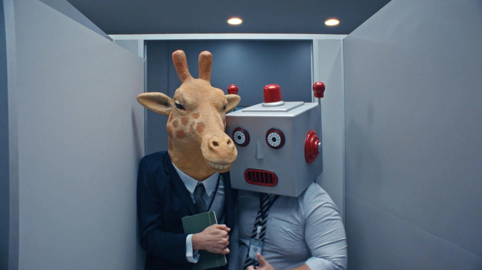 Two office workers in giraffe and robot masks squeezed into a bathroom stall