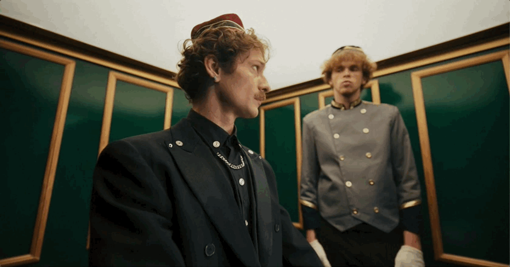 Two hotel staff in uniform standing in a green-walled corridor