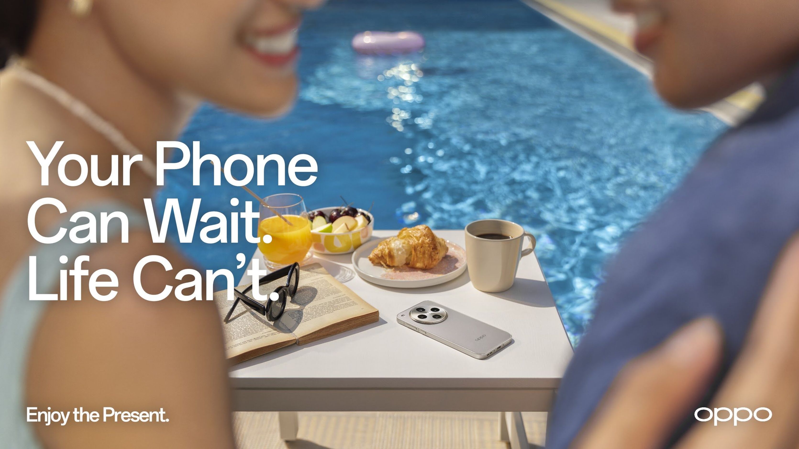Key visual of friends by a pool with a phone face down on the table