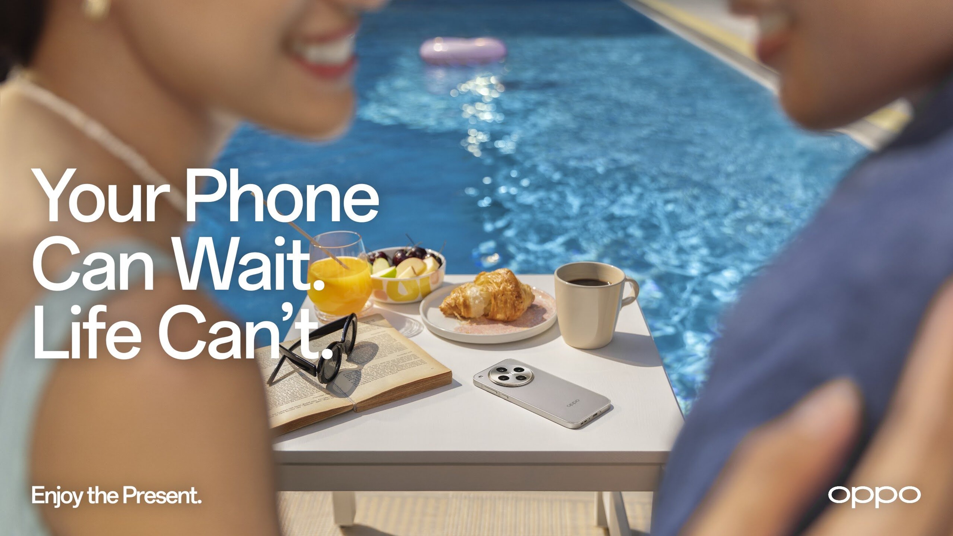 Key visual of friends by a pool with a phone face down on the table