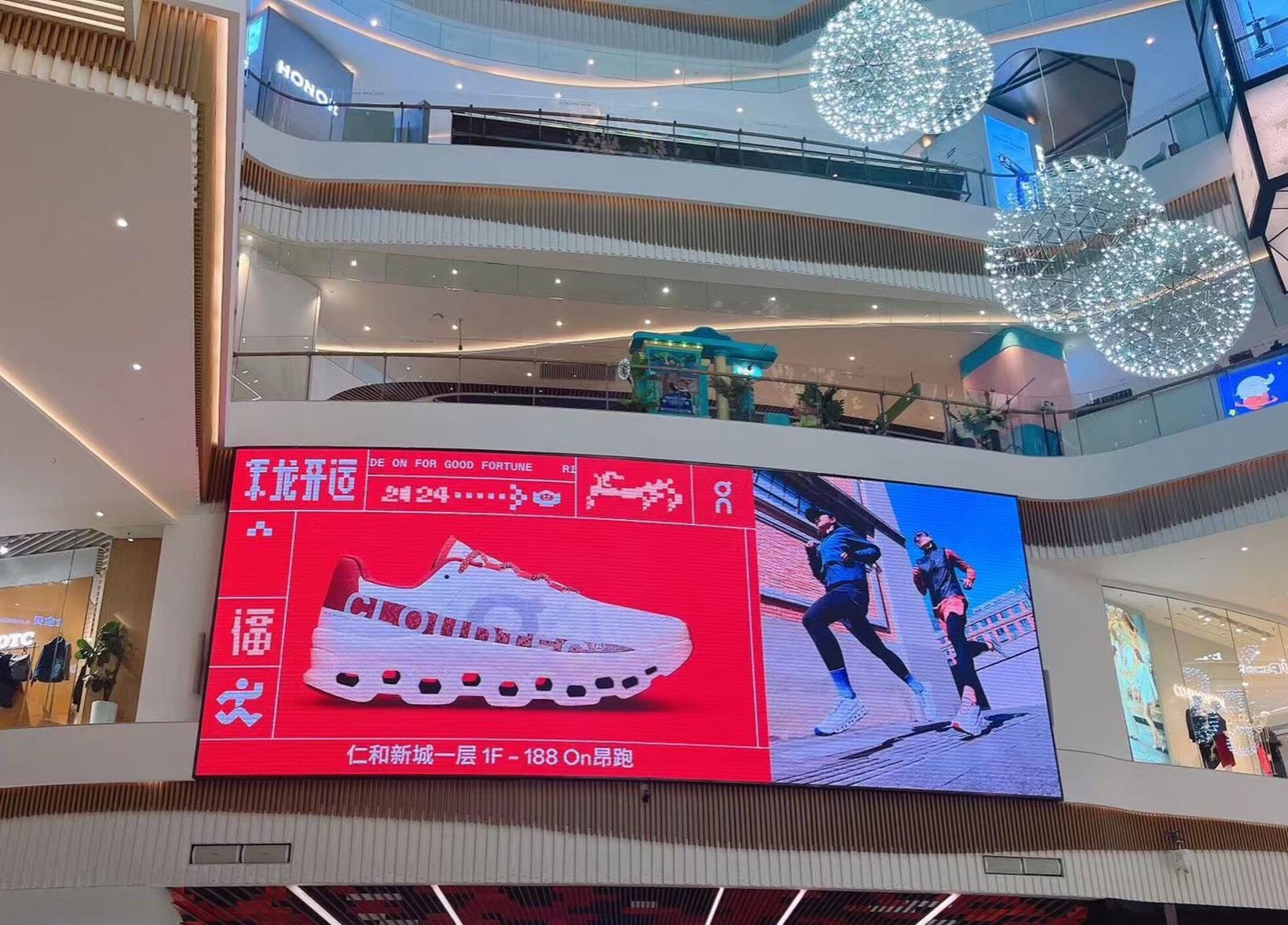 Large digital screen showing the Cloudmonster inside a shopping mall atrium