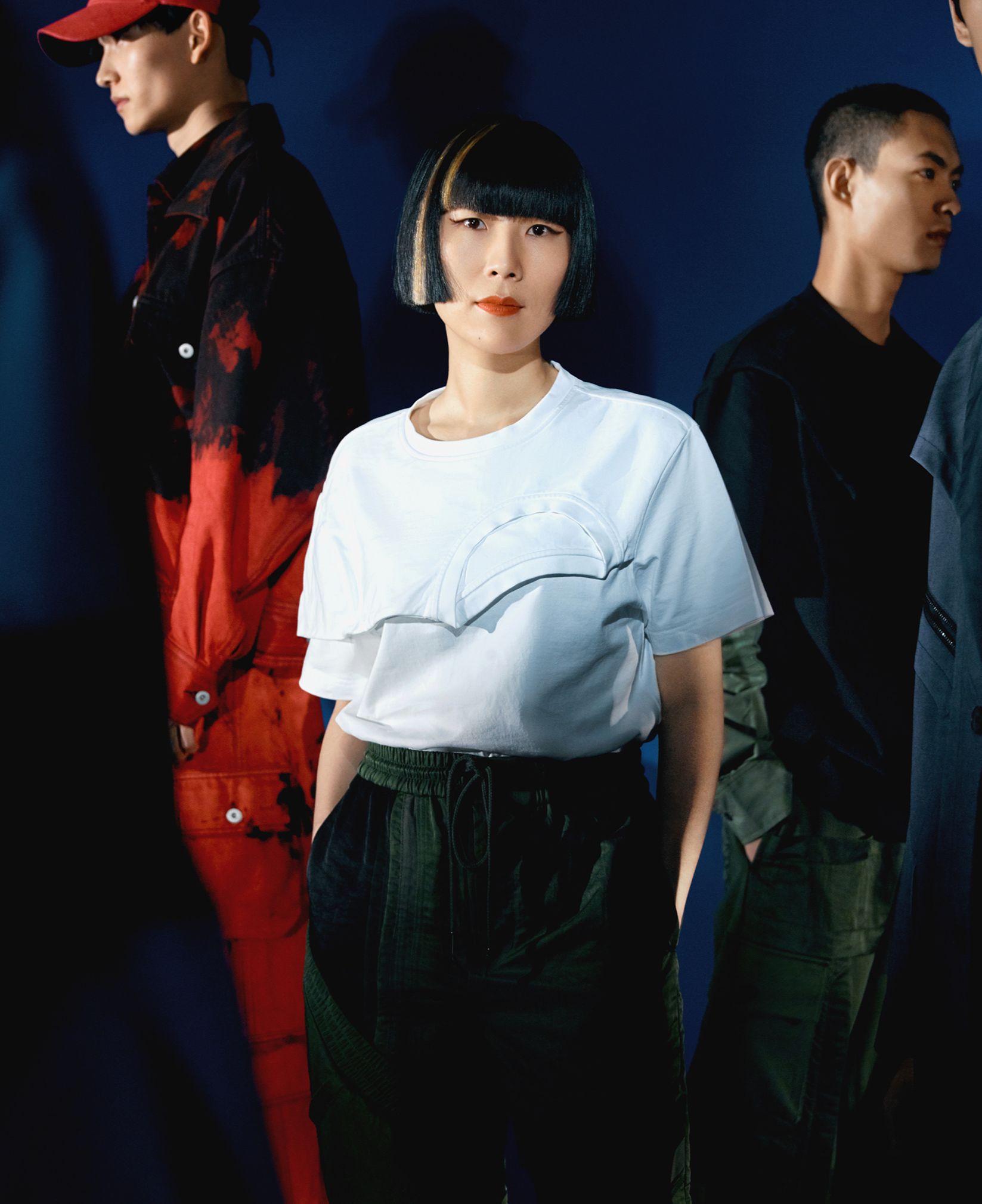 Three young creatives in streetwear against a dark blue background