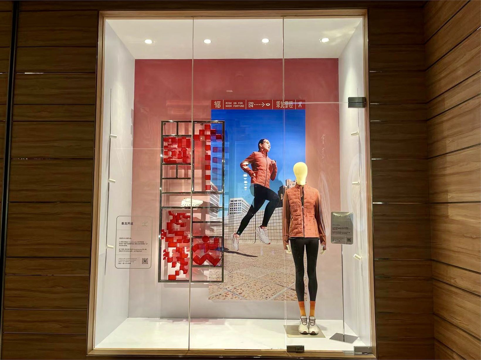 On store window with red pixel charm installation and mannequin in a red jacket