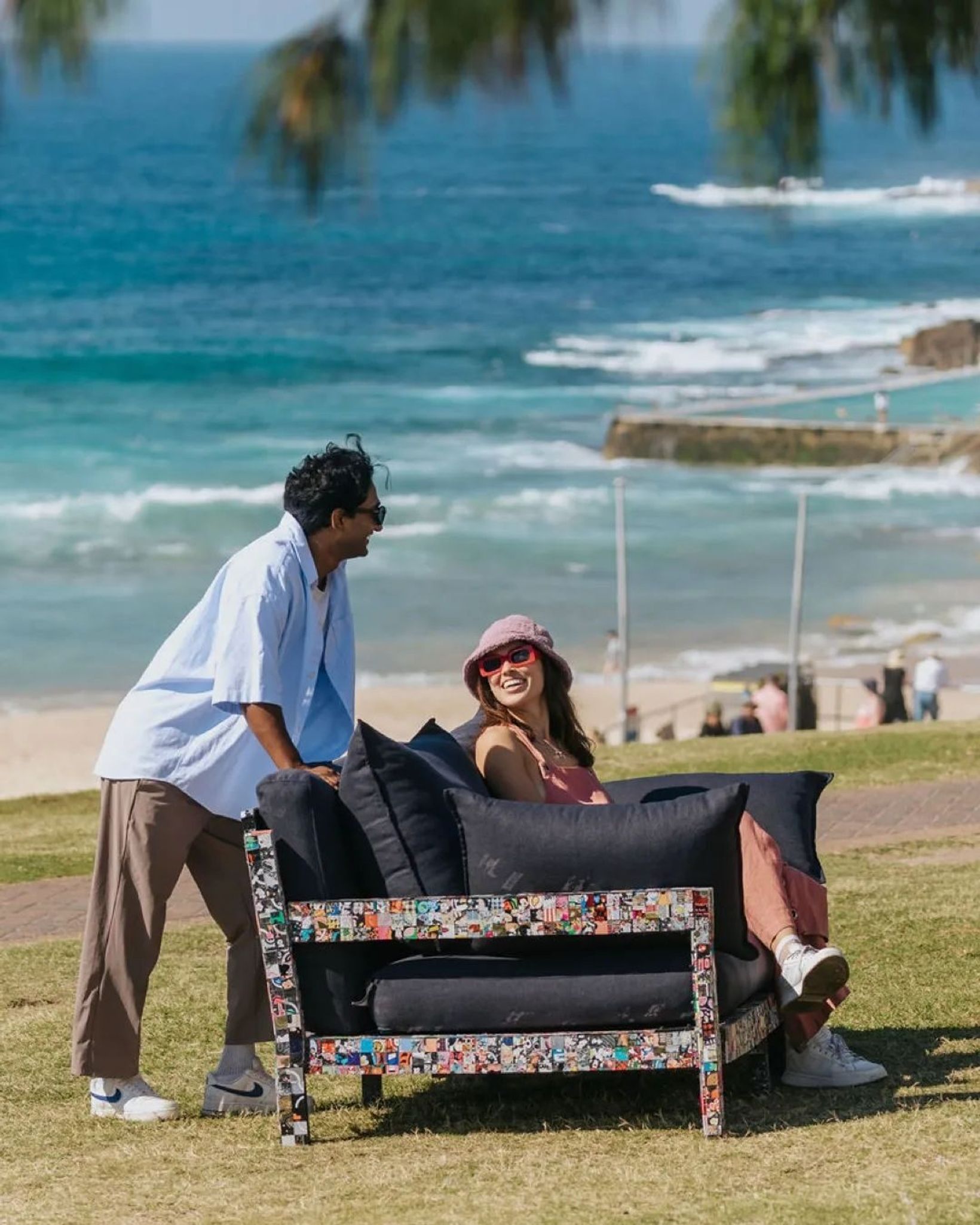 Couple sitting on a sofa made from recycled phone cases by the sea in Australia