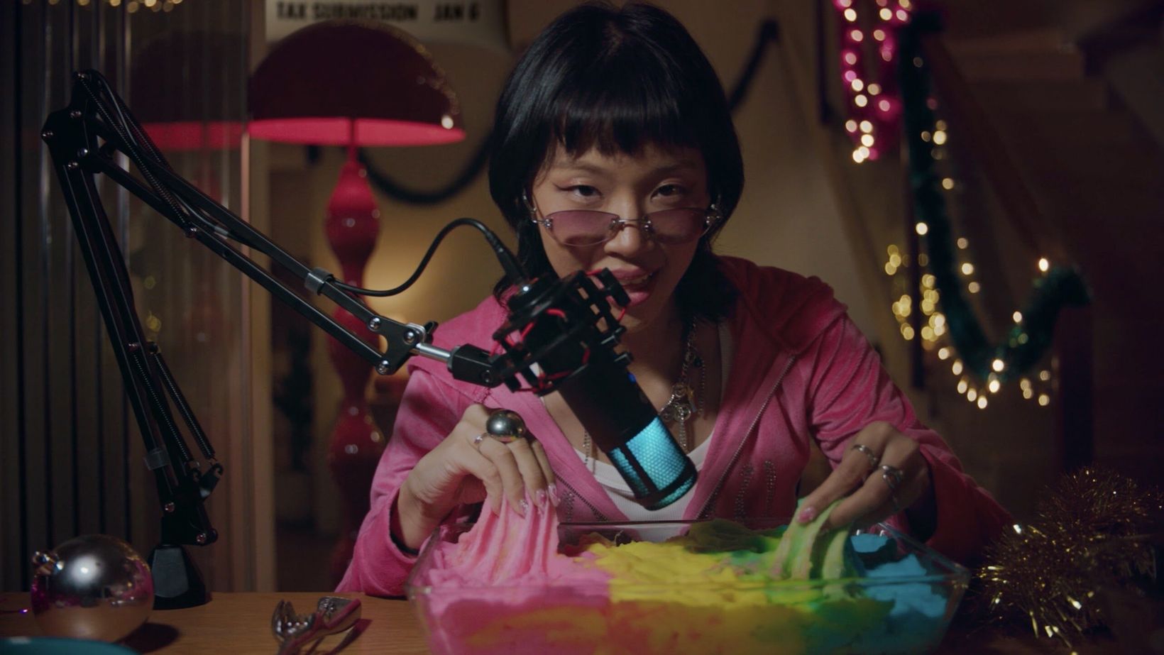 Film still of an ASMR host whispering into a microphone at the table