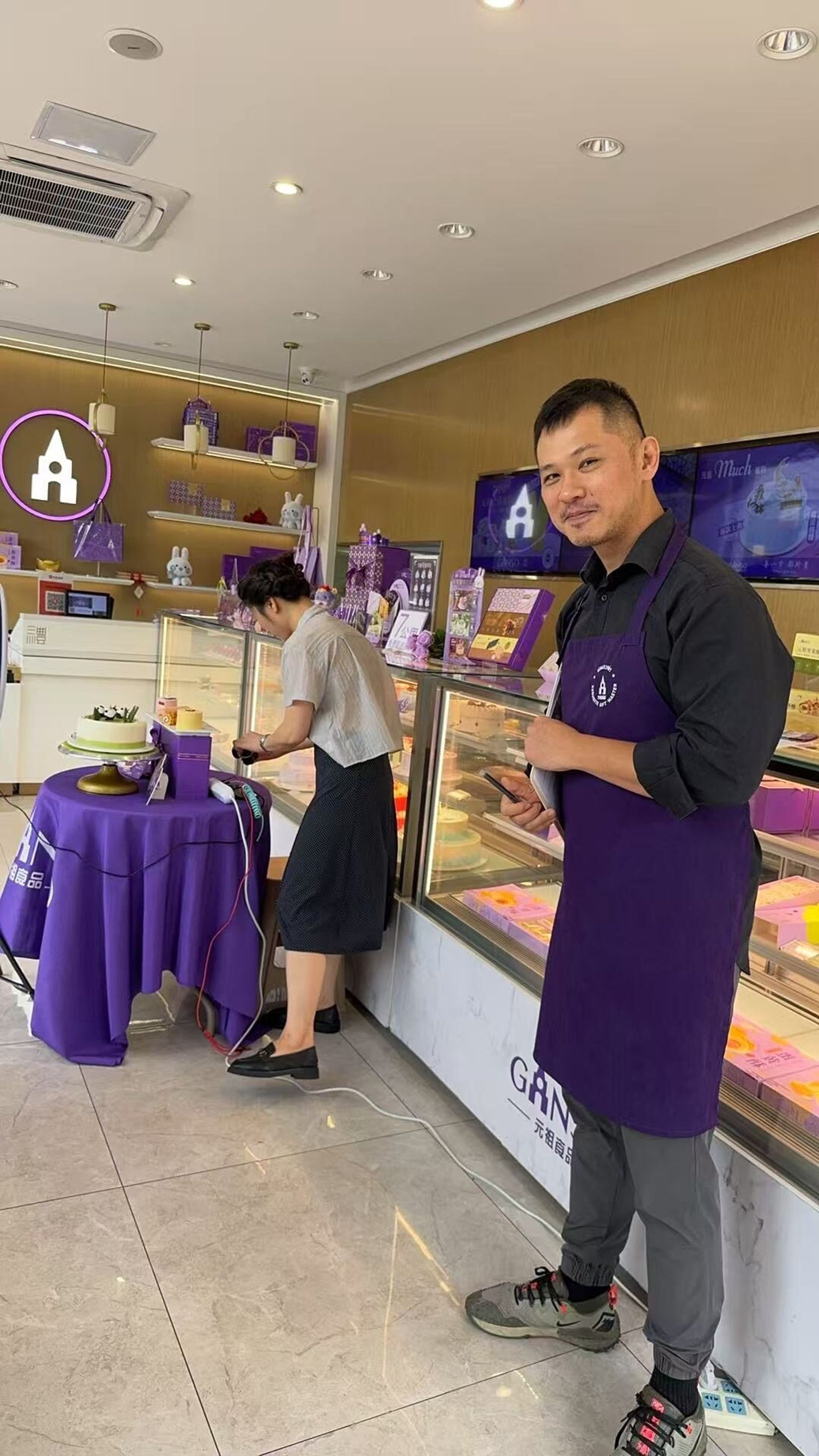GANSO store staff member in an apron beside a purple display