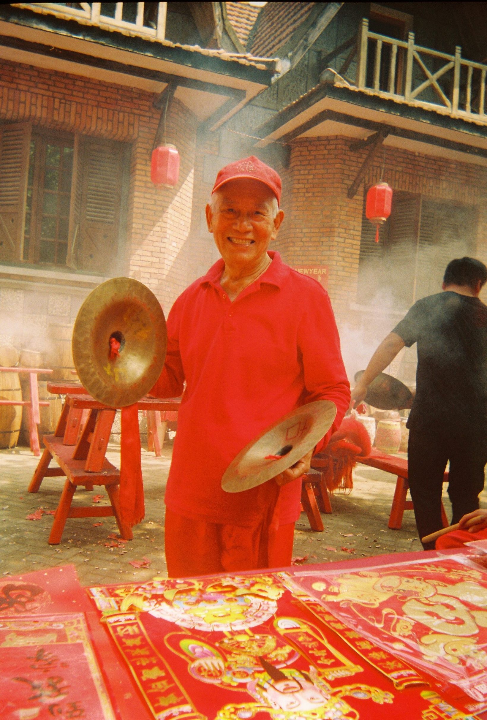 Behind the scenes: man in a red outfit clashing cymbals on set