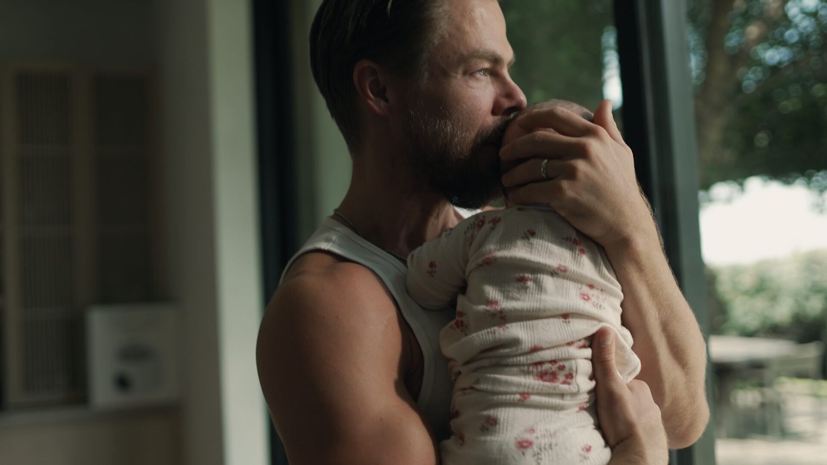 Derek Hough kissing his baby by the window
