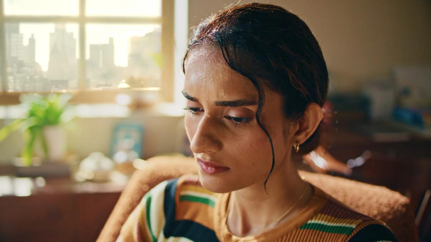 Young woman looking down at her phone in a sunlit living room