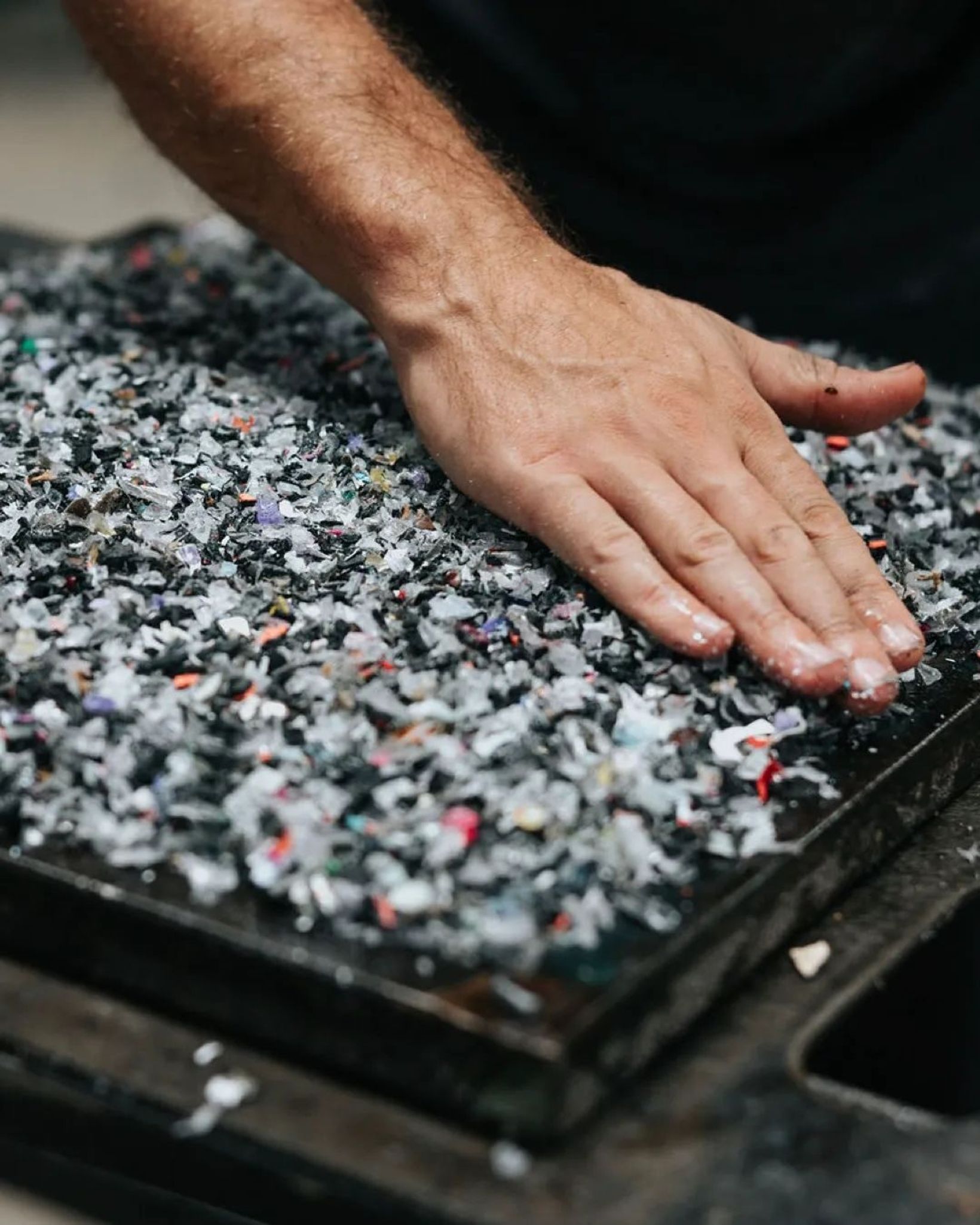 Hand pressing into a surface made of shredded recycled phone cases