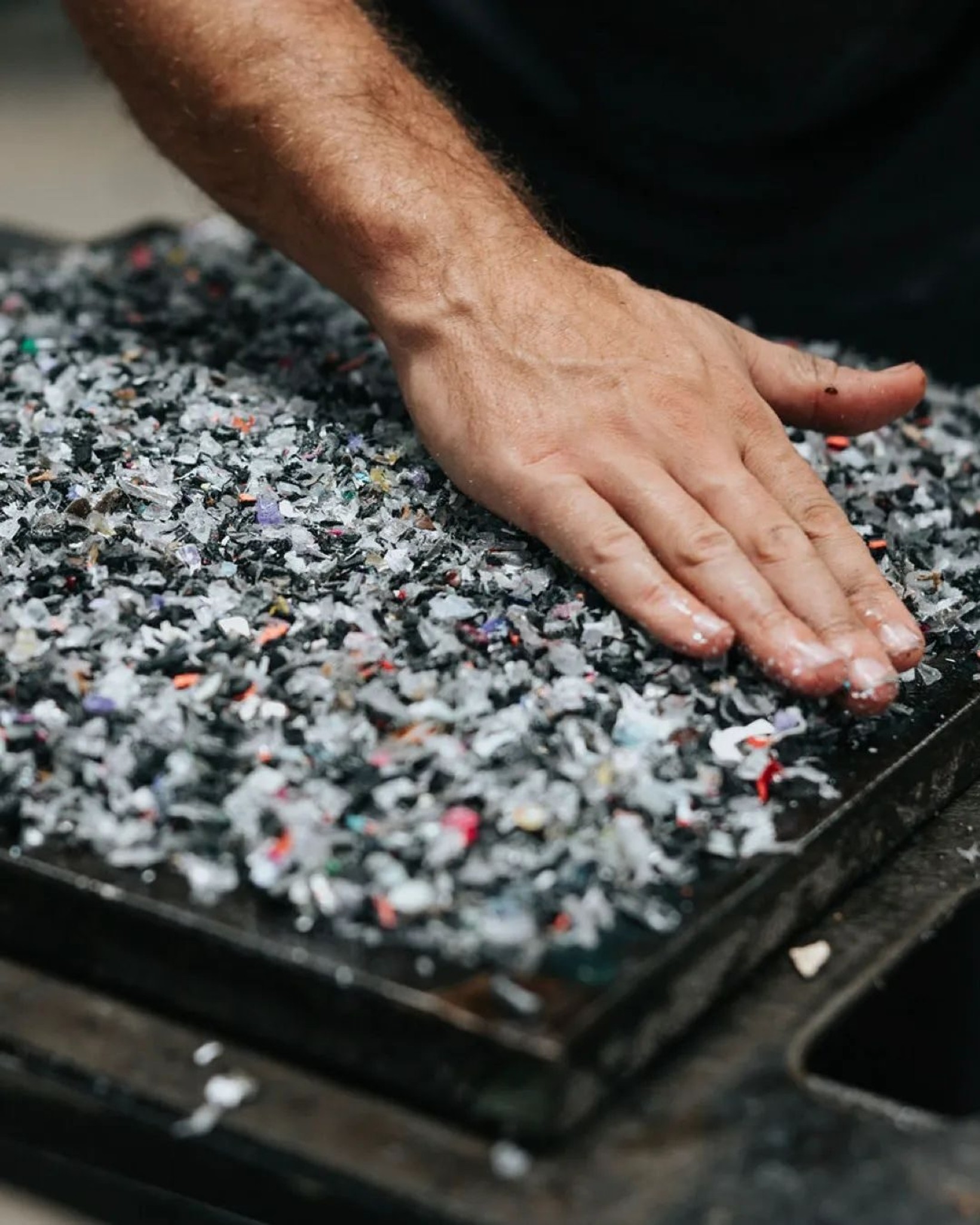 Hand pressing into a surface made of shredded recycled phone cases