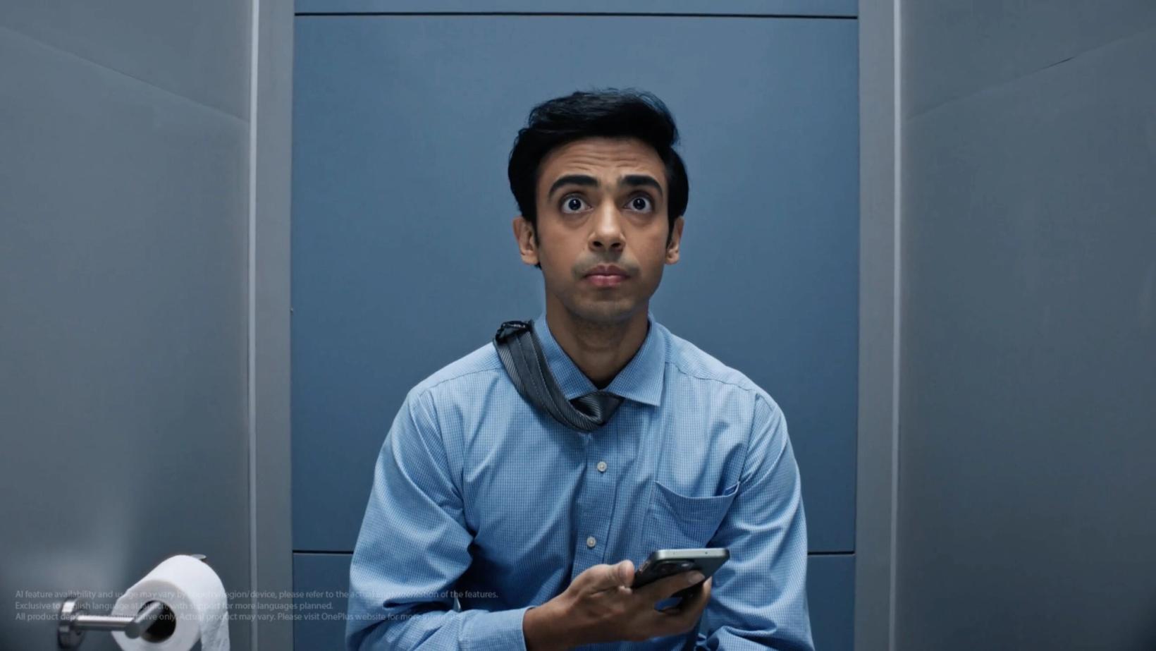 Office worker in a blue shirt holding his phone in a bathroom stall
