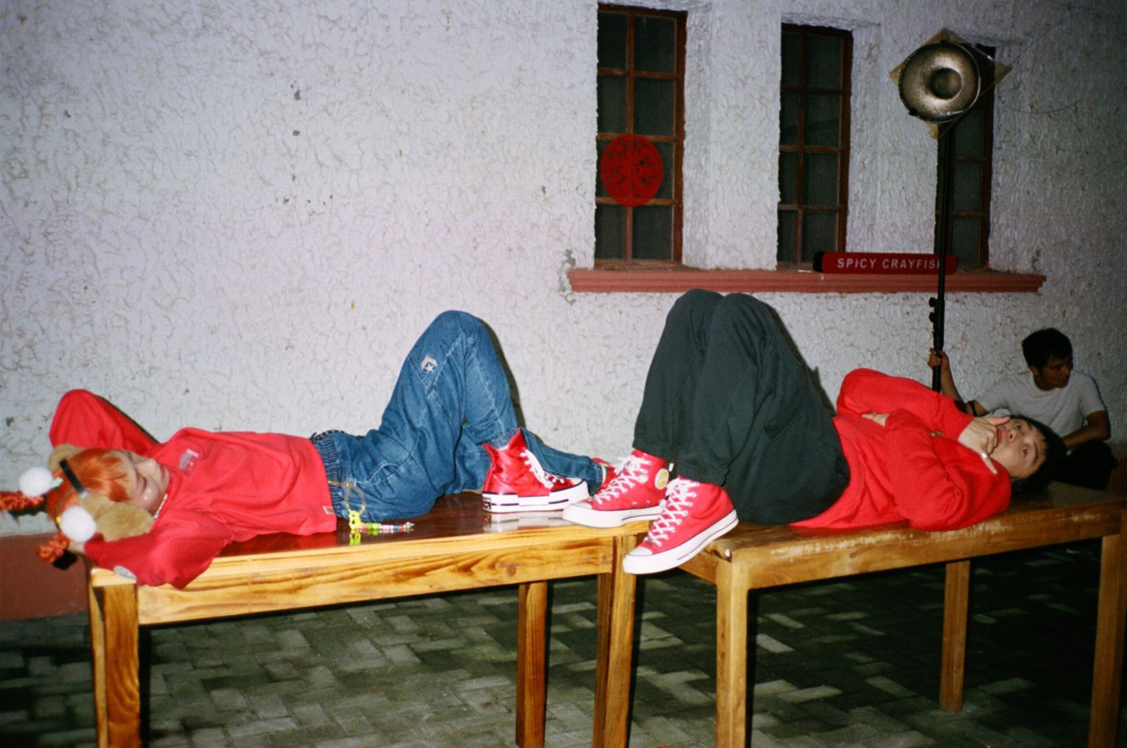 Behind the scenes: two cast members lying on benches in red Converse