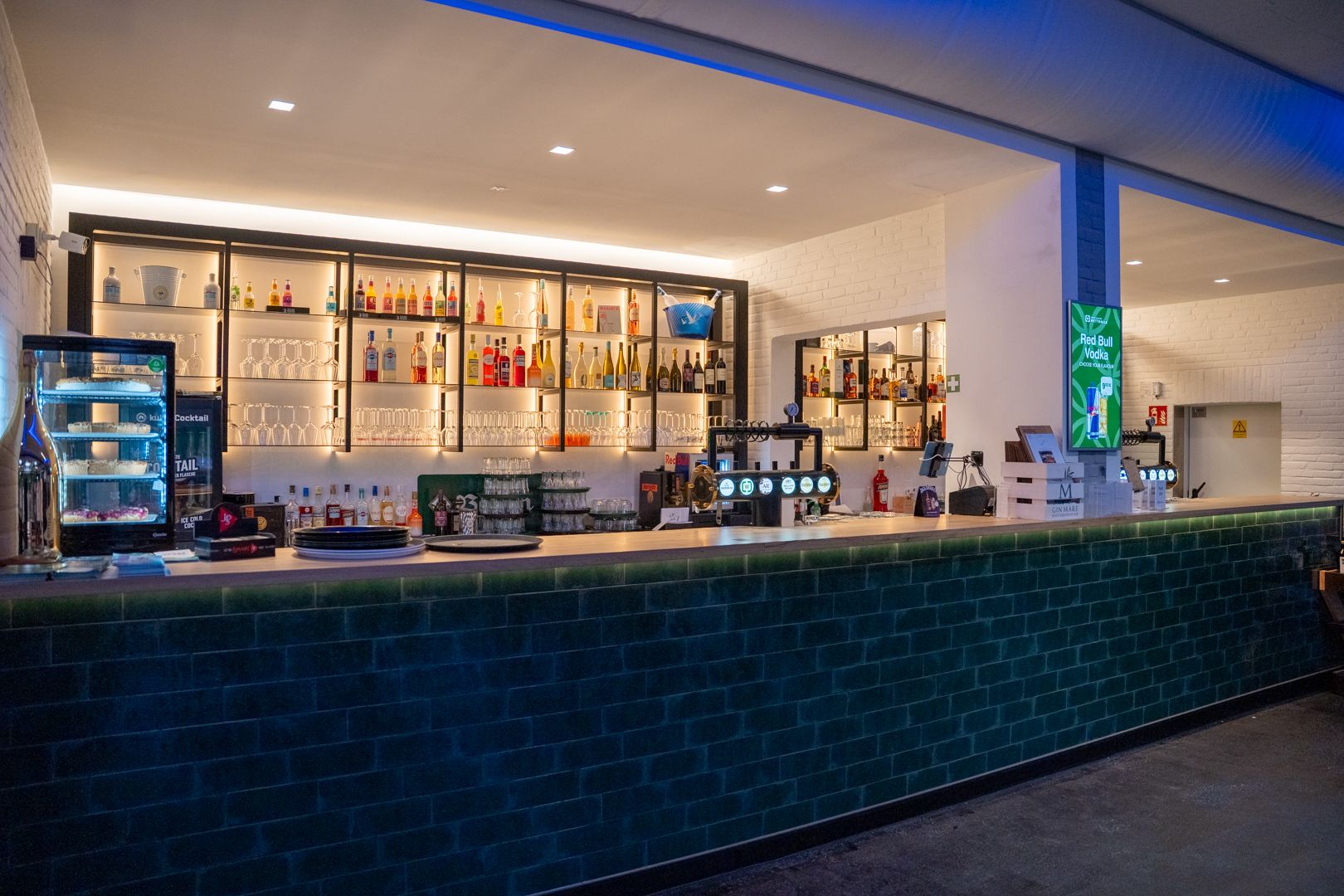 Großzügige Eventbar der Wetthalle Neuss mit grün gefliester Theke, hinterleuchtetem Spirituosenregal, Cocktail-Kühlung, Zapfanlage und Red-Bull-Display