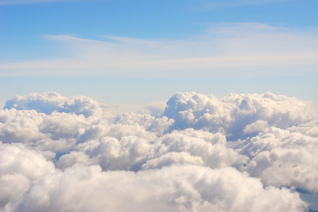 Een uitgestrekt wolkendek van bovenaf gezien, onder een open blauwe hemel.