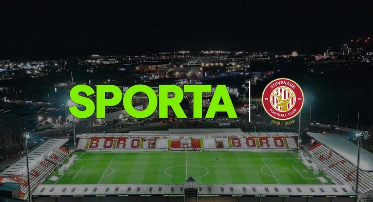 Logos of SPORTA and Stevenage FC against a backdrop of the SPORTA Arena at night.