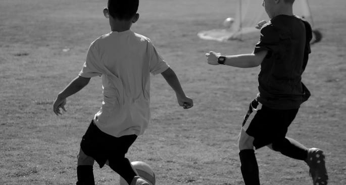 Two young boys playing football on a football pitch.
