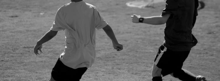 Two young boys playing football on a football pitch.