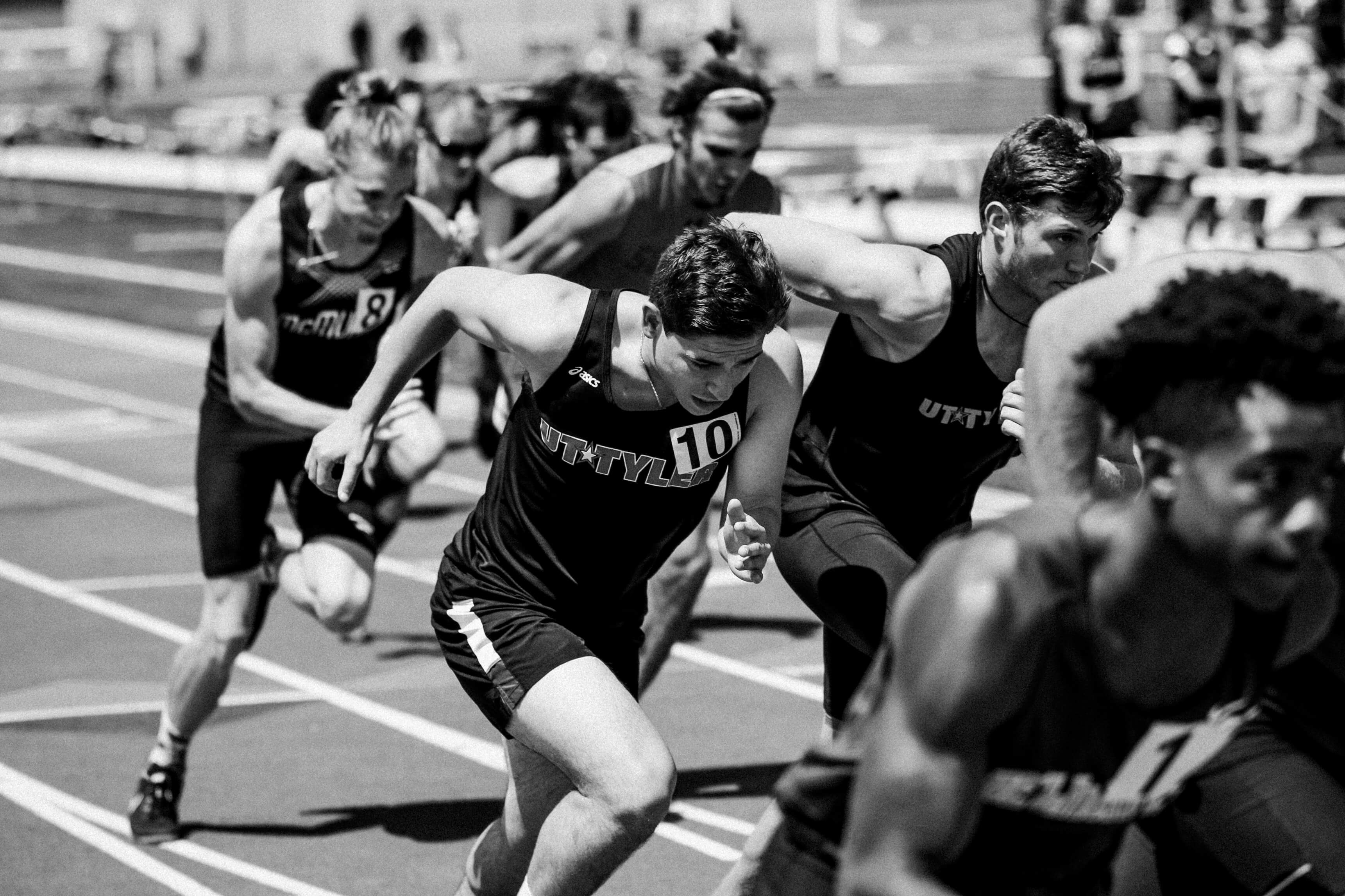 Male athletes running on a track.