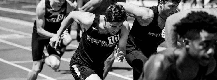 Male athletes running on a track.