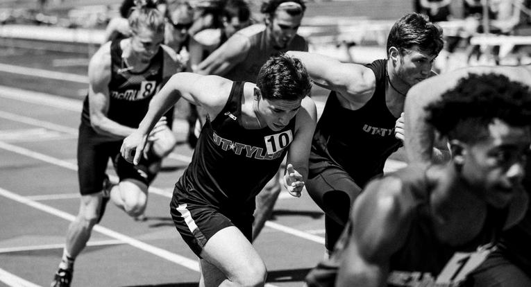 Male athletes running on a track.