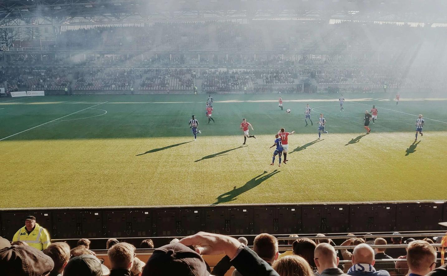 Football players playing football in a sunny stadium.