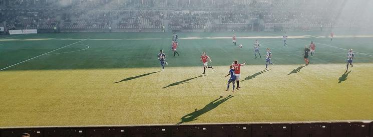 Football players playing football in a sunny stadium.