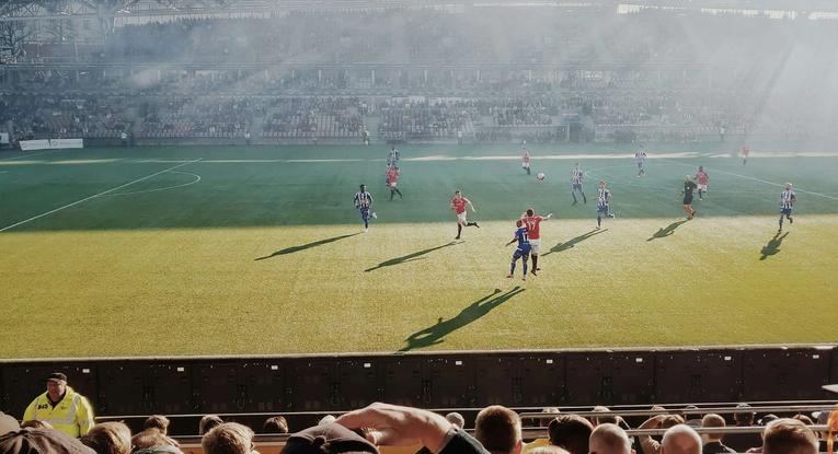 Football players playing football in a sunny stadium.