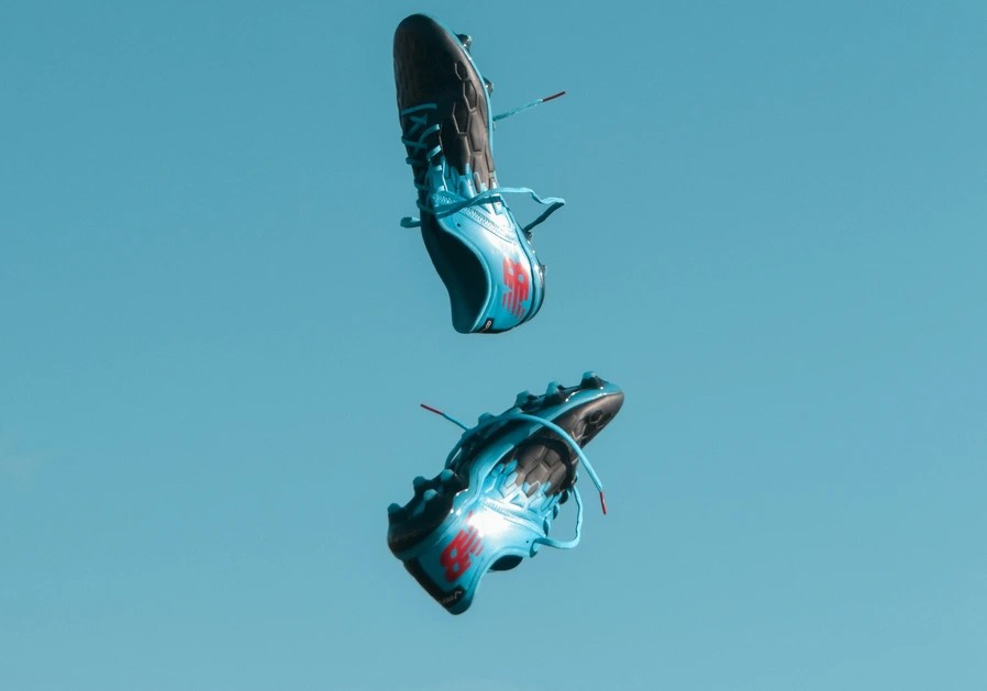 A pair of football boots thrown into the air with the sky in the background.