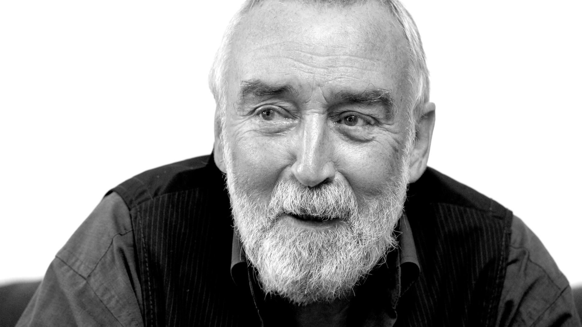 Black and white portrait of a smiling man with a white beard.